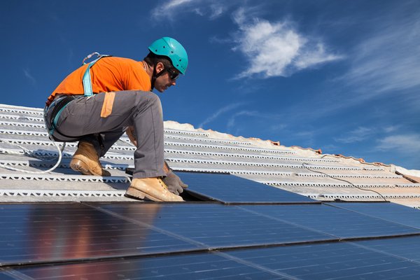 Man installing solar panels on a roof.