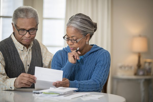 Two people carefully review paperwork at dining table.