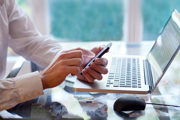 Person looking at phone while using a computer.