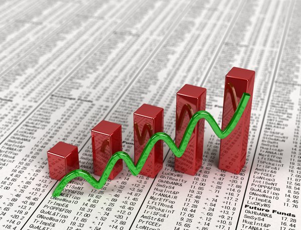 An ascending green line and bar chart on a financial newspaper with stock quotes