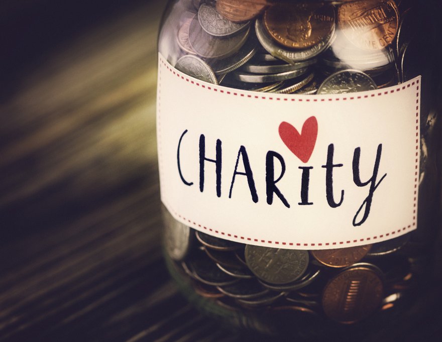 Coins in a glass jar labeled Charity.