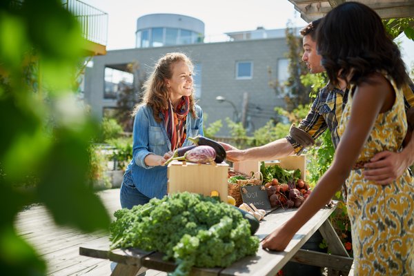 Two people buying food from farmer at farmers market