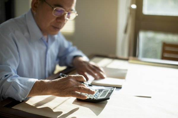 Person sitting at table and calculating finances.