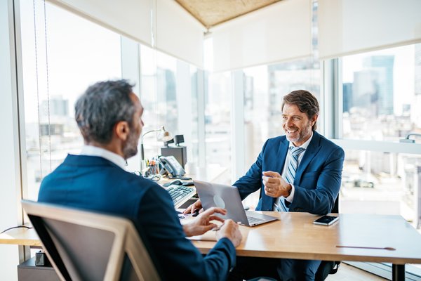 Two people talking over a desk in an office.