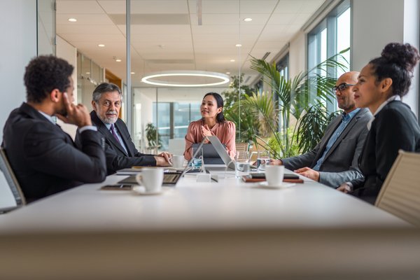 People sitting at a table and talking with one another in a boardroom.