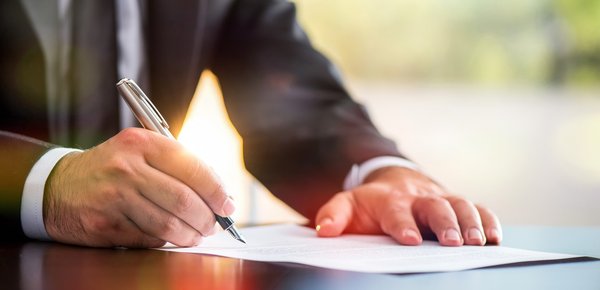 Person in business suit signs paperwork.