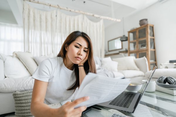 Person looking worried while reviewing paperwork in living room.