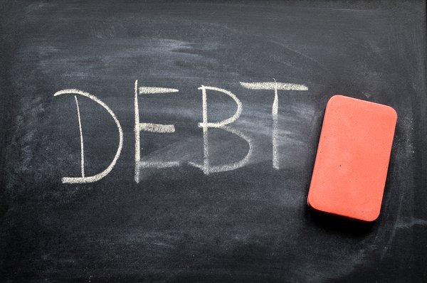 The word Debt on a chalkboard being erased by an orange eraser.