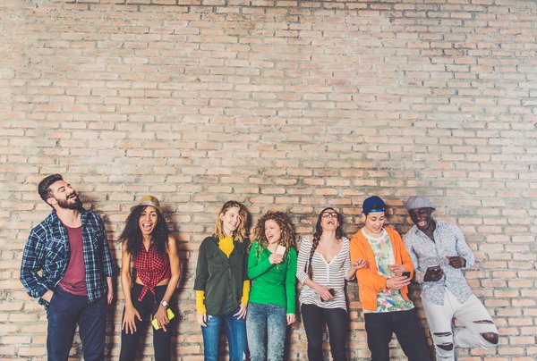 Group of teenagers hanging out by a brick wall.