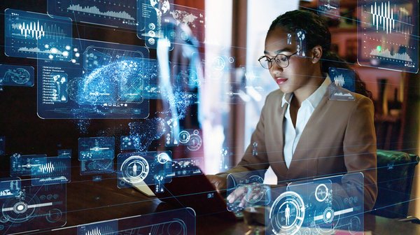 Young woman at computer with digital data images around her.