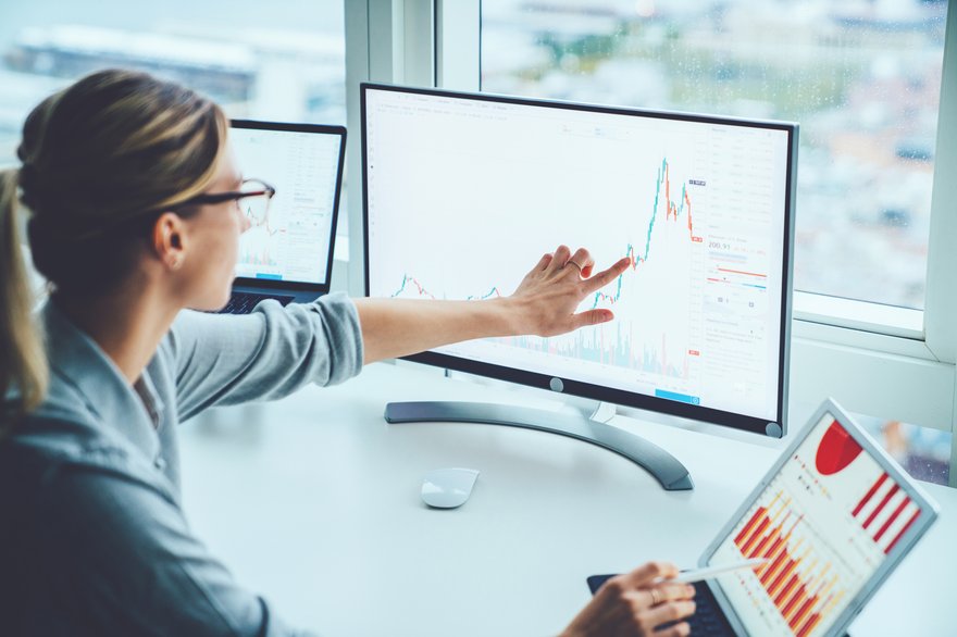 Person points to graph on monitor showing volatility.