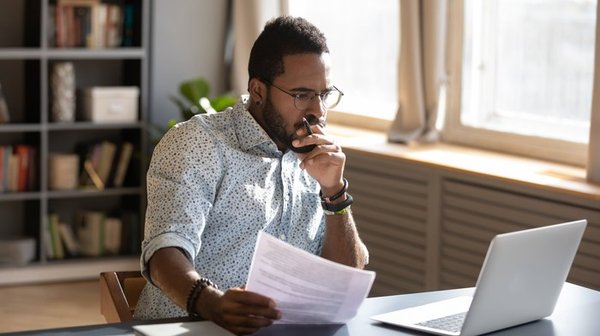 Person at home in front of laptop researching investments.