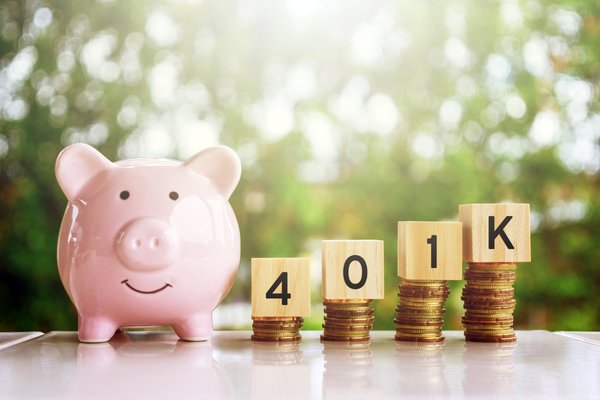 Smiling piggy bank next to rising stacks of coins topped with blocks saying 401k.