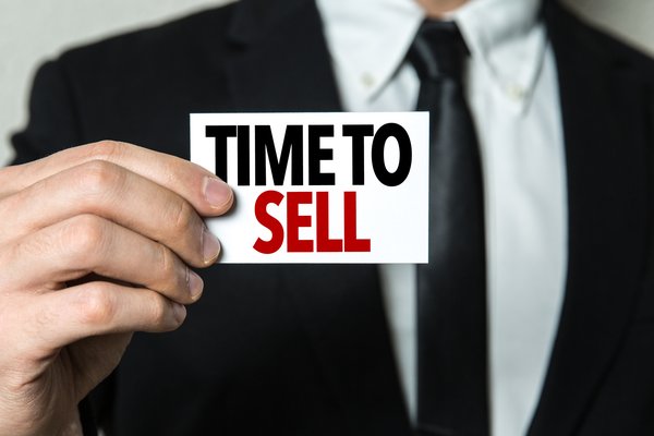 man in business suit holding sign that says time to sell