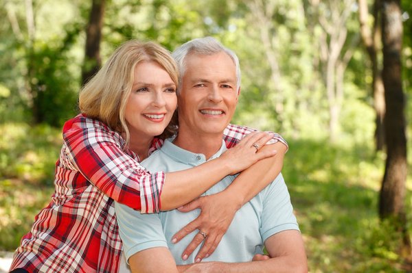 A woman hugging her husband while sitting outdoors and smiling