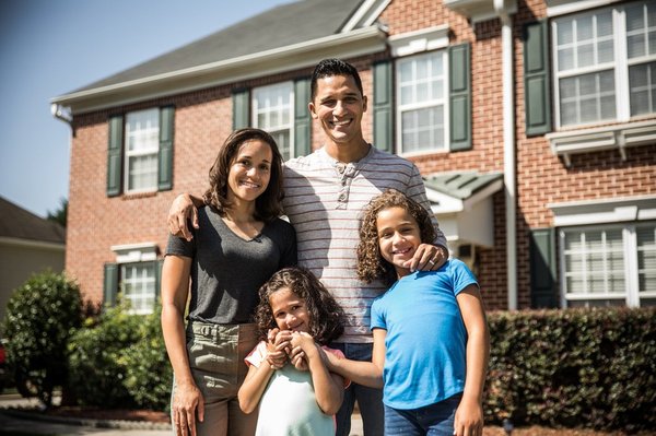 Family of four in front of house.