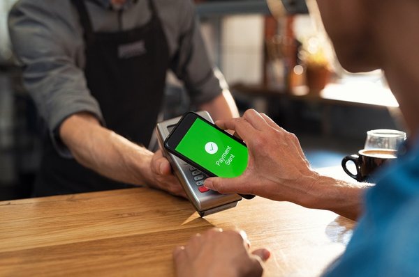 Person using a mobile phone to make a payment in a store. 