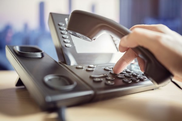 Person using a telephone on a desk.