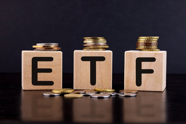 Coins sit atop of wooden blocks that spell out ETF.