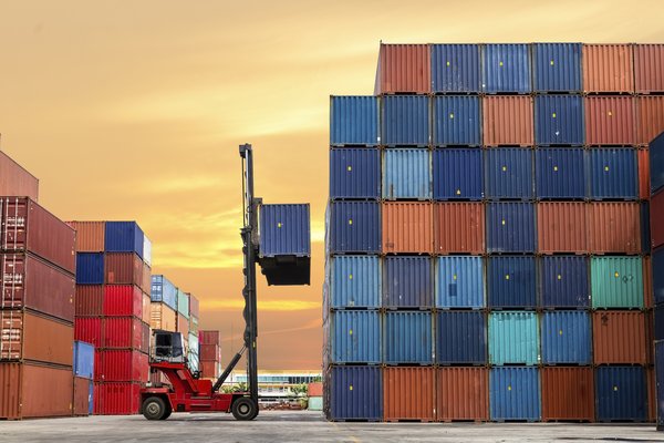 Shipping containers being moved in cargo yard.