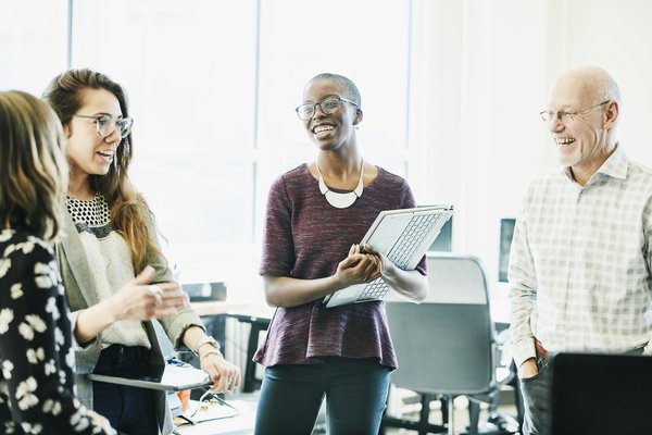 Co-workers smiling and talking with one another in an office.