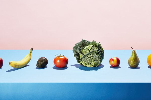 Vegan foods, all types of fruits and vegetables lined up on a blue table.