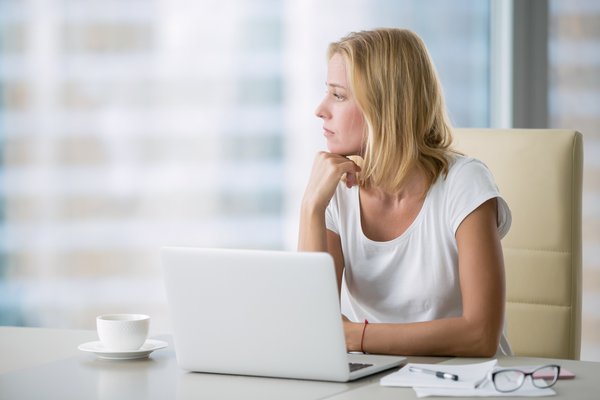 Person at a laptop gazing out the window.