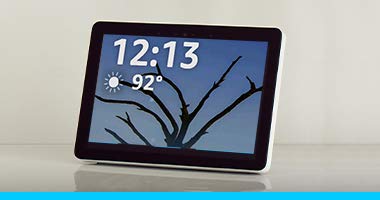 An Echo Show screen shows a magnified time and temperature on a background of a tree branch at dusk.