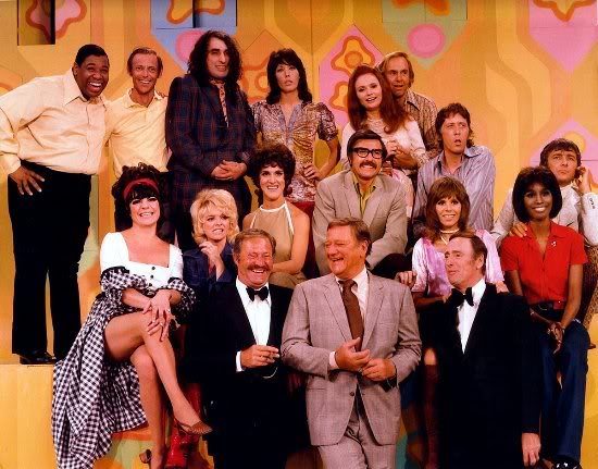 John Wayne, Lily Tomlin, Dennis Allen, Johnny Brown, Ruth Buzzi, Judy Carne, Richard Dawson, Ann Elder, Teresa Graves, Larry Hovis, Dick Martin, Gary Owens, Dan Rowan, Barbara Sharma, Alan Sues, Tiny Tim, and Jo Anne Worley in Rowan & Martin's Laugh-In (1967)