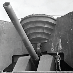 A British soldier stands in front of a captured 380-mm German cannon at the Atlantic Wall.