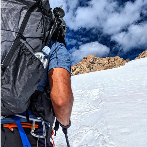 Main wearing a Pima Crew Neck T-shirt while hiking on a snowy mountain 