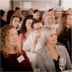 Group of professional women sitting at tables at a networking event