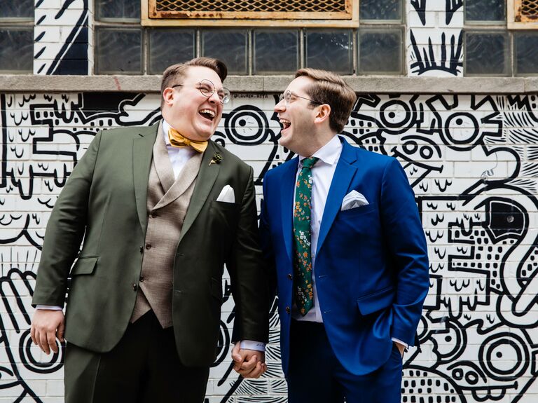 Cute Couple Poses: Couple laughs in front of a modern mural. 