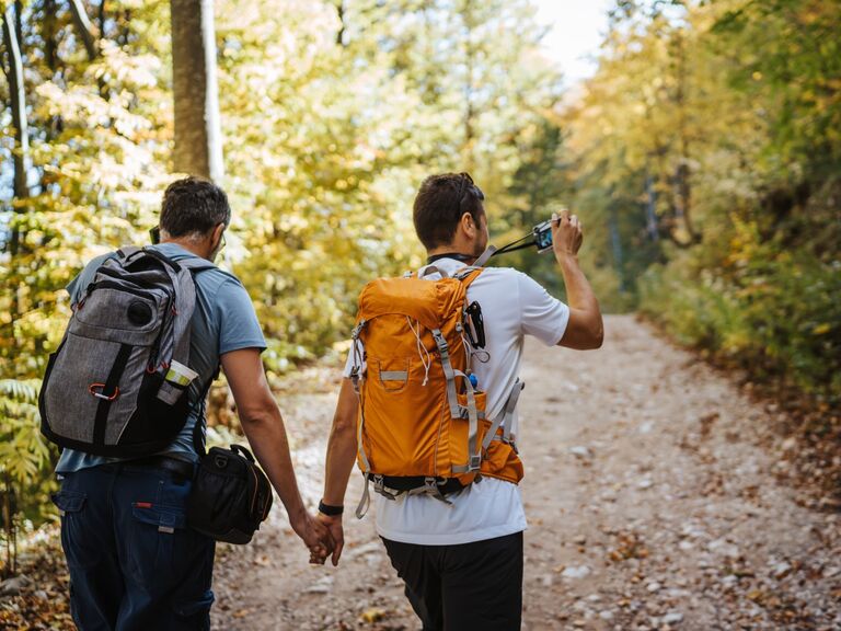 Couple hikes down a beautiful trail in the forest. 