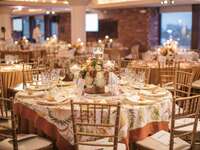 Close up of decorated event table surrounded by gold Chivari chairs