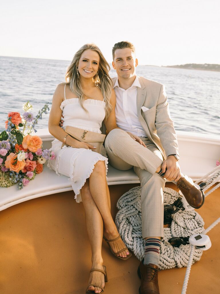 Couple Poses: Couple sits on the bow of a sailboat while smiling at the camera. 