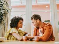 A couple smiles at each other while lost in a deep conversation. 