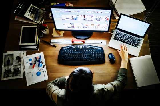 Image: Casual young businesswoman working late on a computer and laptop