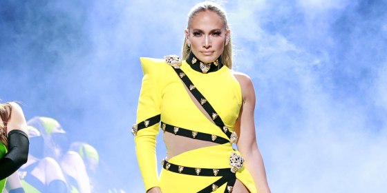 Jennifer Lopez in a one-shoulder bright yellow dress in front of smoke on stage at the Global Citizen VAX LIVE: The Concert To Reunite The World.