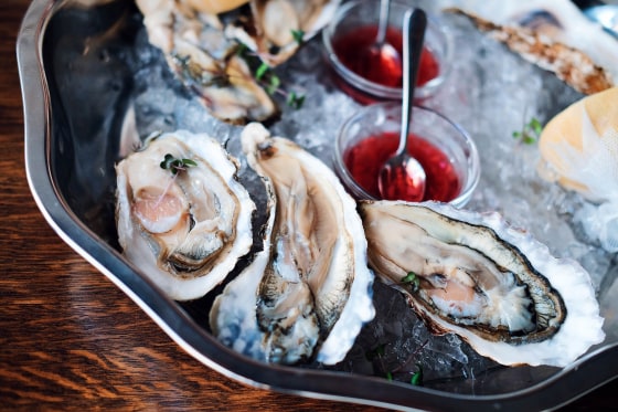 Oysters are on a plate with ice and sauce