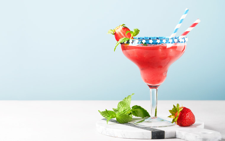 Glass margarita cocktail with strawberry, mint, and red white and blue colors.