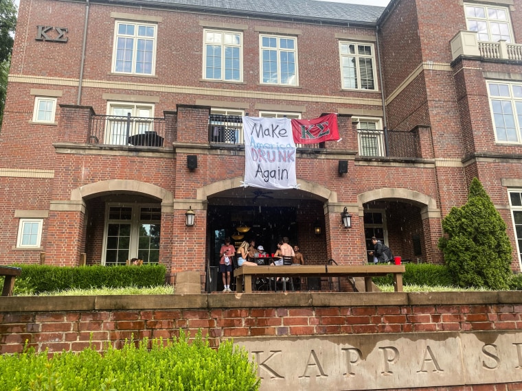 People can be seen partying in a house under a banner that says "Make America DRUNK Again"