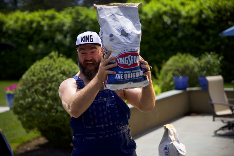 Jason Kelce holding a bag of Kingsford charcoal.