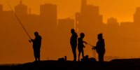 San Francisco skyline behind as people fish in the foreground