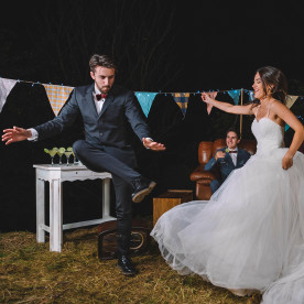 Happy bride and man dancing on a night field party