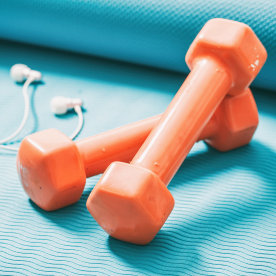 Dumbbells and a smartphone on a blue yoga mat