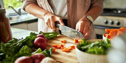 Female hands cutting vegetables on cutting board, preparing a healthy meal.