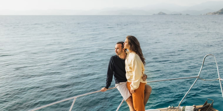 Young couple hugging and enjoying evening on board of luxury yacht. Sailing adventures, travel aboard