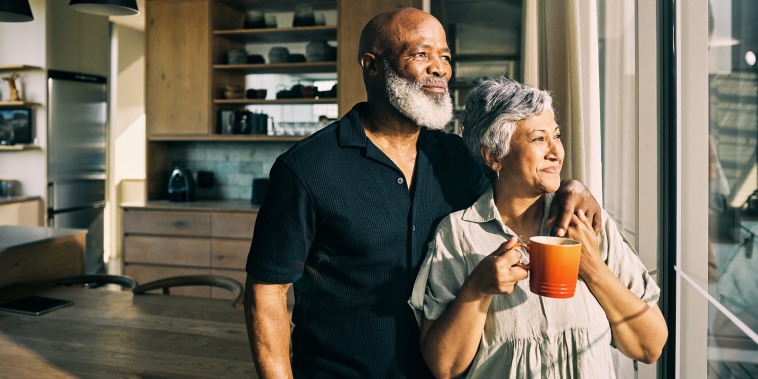 African-American mature couple looking out the window of their home enjoying a moment of togetherness.