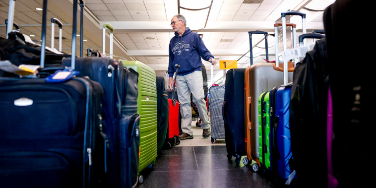 A traveler searches for a suitcase in a baggage holding area